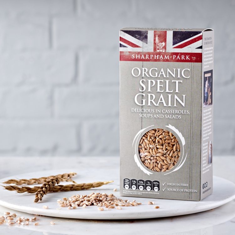 Photo showing the Sharpham Park Organic Spelt Grain box on a white surface with a white bowl and loo