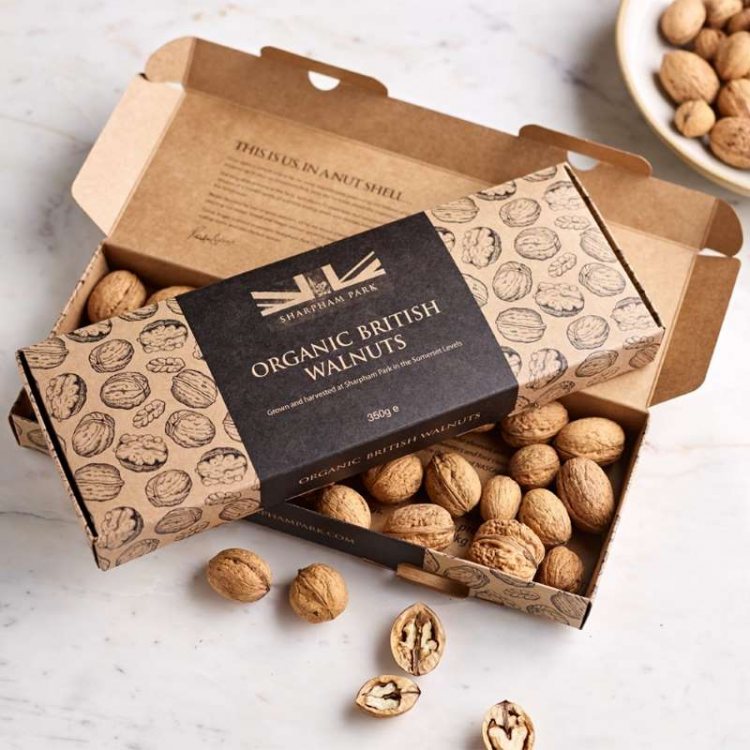 Photo showing the Sharpham Park Organic British Walnuts box open on a white surface with loose walnu