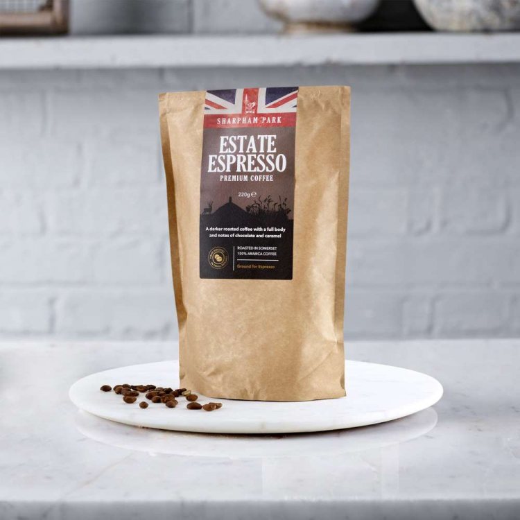 Photo showing the Sharpham Park Estate Espresso Premium Coffee bag on a white surface with loose cof