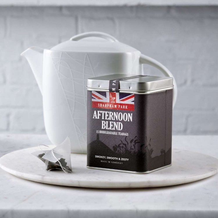 Photo showing the Sharpham Park Afternoon Blend Tea Bags box on a white surface with a white teapot 