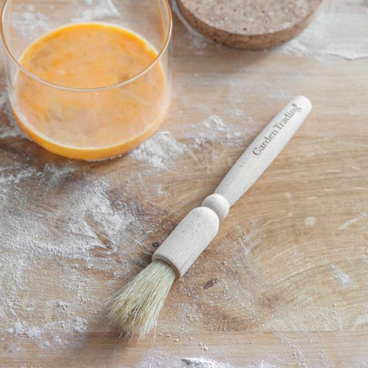 Photo showing the Garden Trading Pastry Brush on a wooden surface with flour dusted over it, with a 