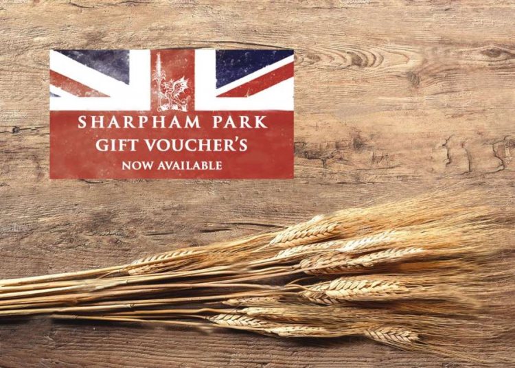 Picture representing the Sharpham Park gift voucher on a wood background and loose wheat grains