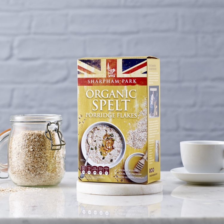 Photo showing the Sharpham Park Organic Spelt Porridge Flakes cereals in a box on a white surface wi