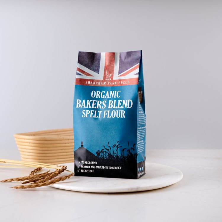 Photo showing the Sharpham Park Organic Spelt Bakers Blend Flour bag on a white surface with a beige